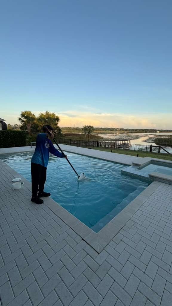 Technician cleaning pool at sunset