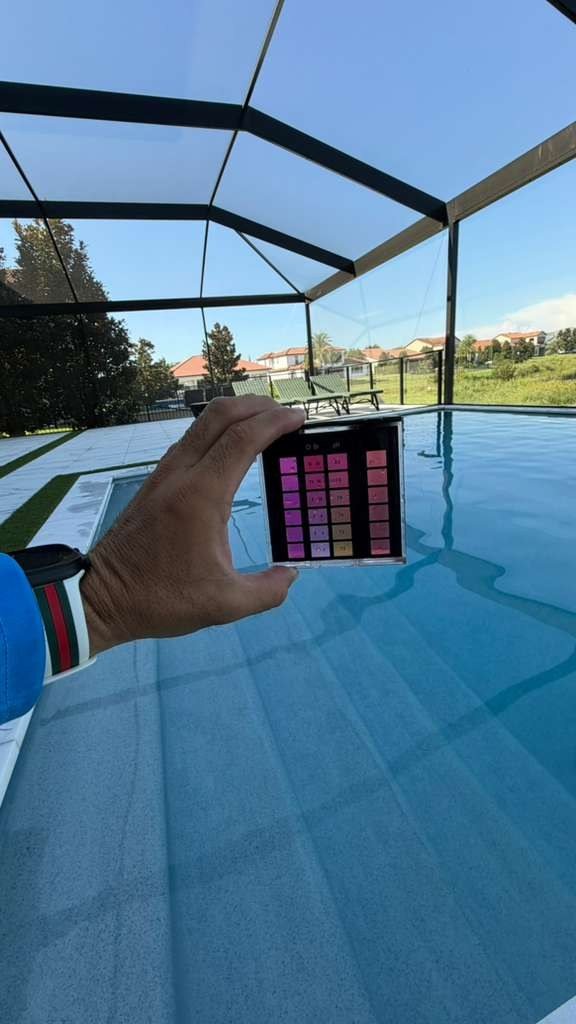 Water testing kit held over a pool
