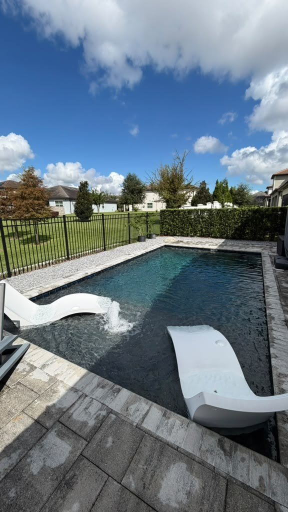 Modern pool with in-water lounger chairs and water feature