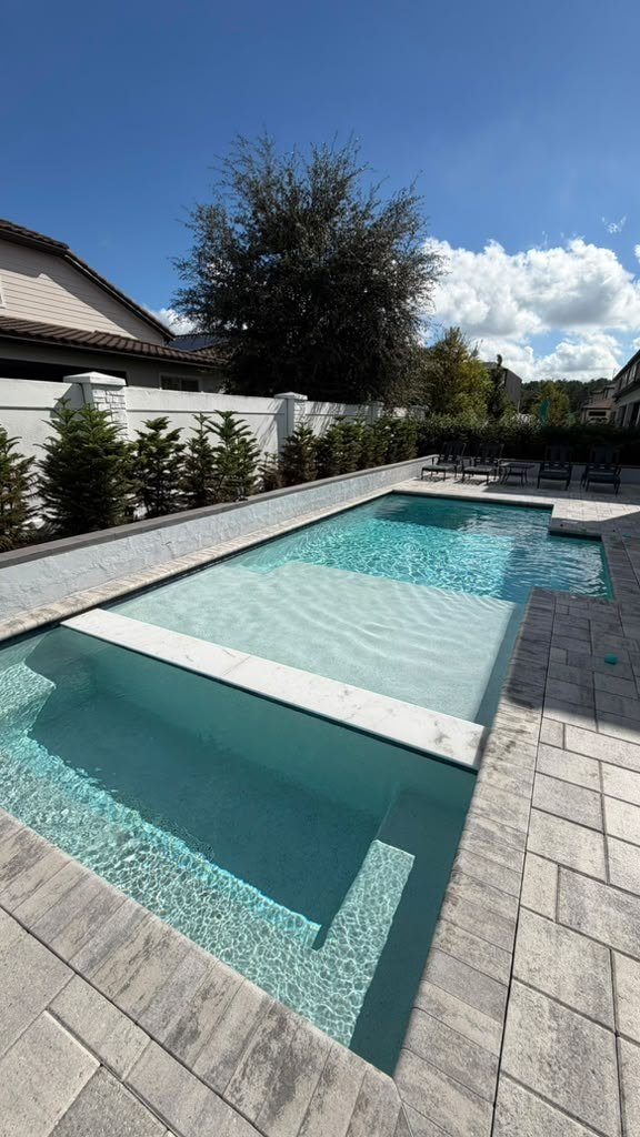 Pool with raised spa and sun shelf, travertine deck